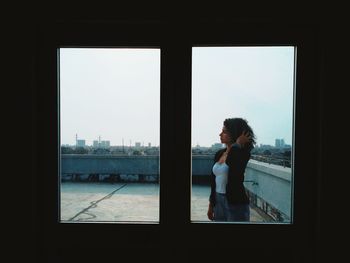 Womman standing by window on rooftop