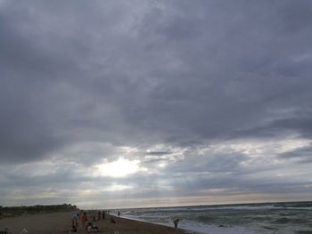 Scenic view of beach against cloudy sky