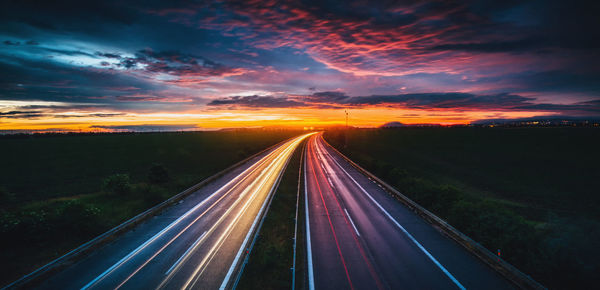 Light trails on highway against sky during sunset