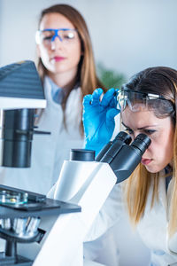 Female scientists using microscope in laboratory