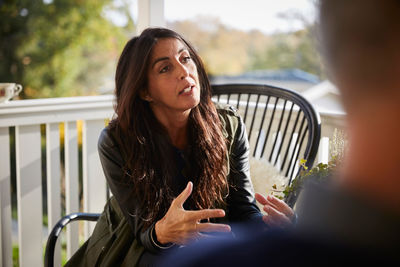 Mature woman gesturing while looking away on porch