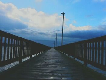 Pier on sea against cloudy sky