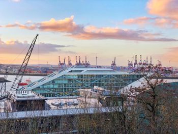 Commercial dock by buildings against sky during sunset