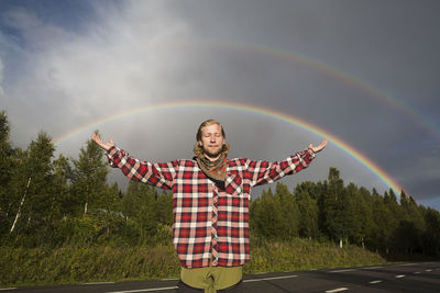 Full length of man standing against rainbow in sky