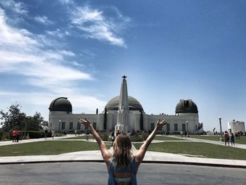 Woman with arms outstretched against sky