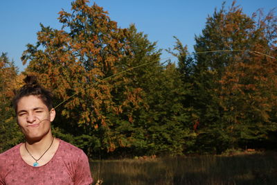 Portrait of young man standing against trees during autumn