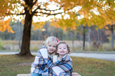 Portrait of smiling girl standing against trees in park