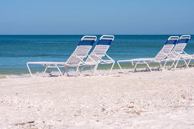 Chairs on beach against blue sky