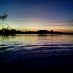 Reflection of trees in water at sunset