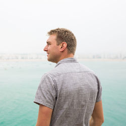 Rear view of man looking away while standing by sea against sky