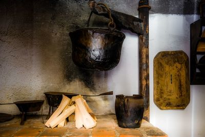 Old cooking utensil hanging over firewood in kitchen at home