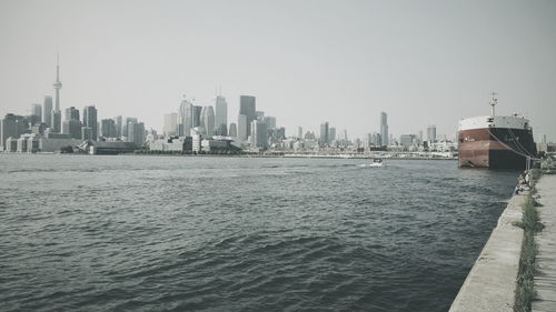 Container ship moored at pier in lake ontario against skyline