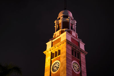Low angle view of clock tower against clear sky at night