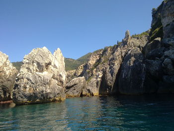 Rock formation and sea against clear blue sky