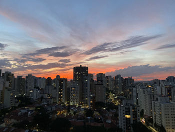Illuminated buildings in city against sky during sunset