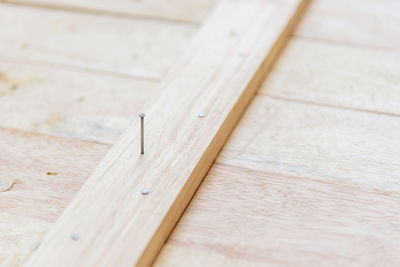High angle view of nail in wooden plank on table