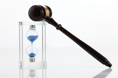 Close-up of gavel with hourglass against white background