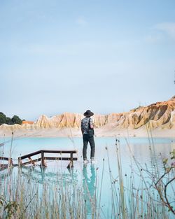 Rear view of man standing by plants against sky