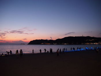 Silhouette people on beach against clear sky during sunset