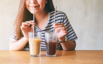 Midsection of woman drinking glass on table