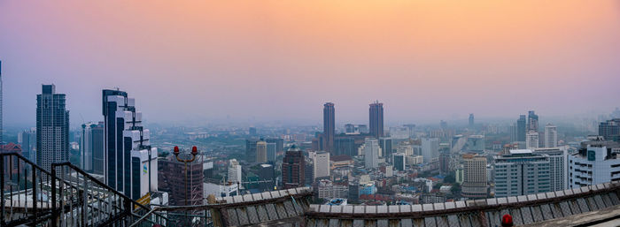Modern buildings in city against sky during sunset