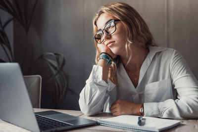 Young woman using mobile phone while sitting in office