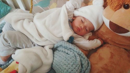 Cute baby boy sleeping on bed at home