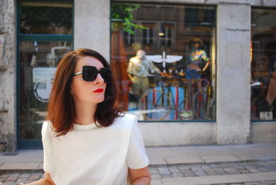 Portrait of young woman wearing sunglasses standing in city