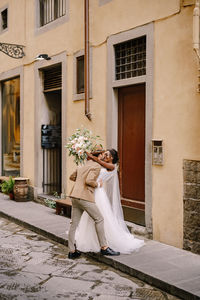 Couple embracing while standing against building in alley