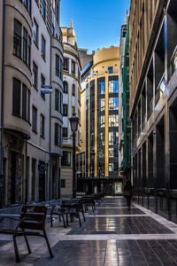 Rear view of woman walking by chairs on footpath in city