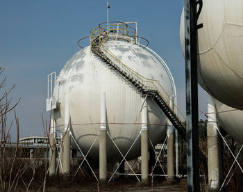 Storage tank at industry against sky