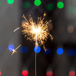 Close-up of sparkler against illuminated background