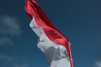 Low angle view of flag against blue sky