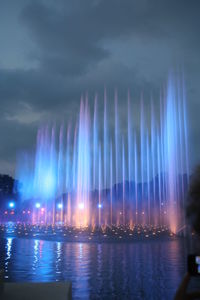 Illuminated fountain against sky at night