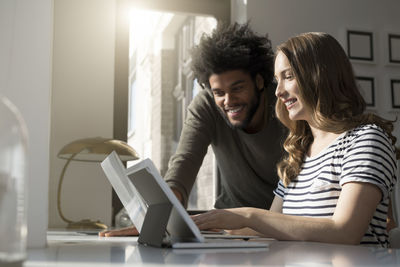 Smiling couple working at home with laptop and tablet