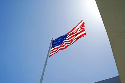 Low angle view of american flag against blue sky