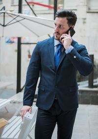 Businessman talking on mobile phone while standing at cafe