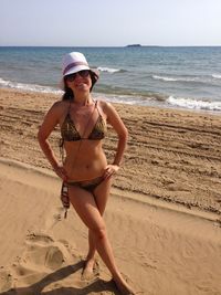 Portrait of sensuous woman in bikini standing at beach