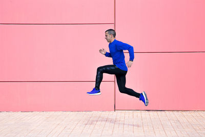 Sporty man exercising on fuchsia wall