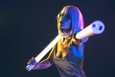 Woman in dress dancing with illuminated lights against black background