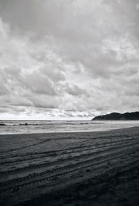 Scenic view of beach against cloudy sky