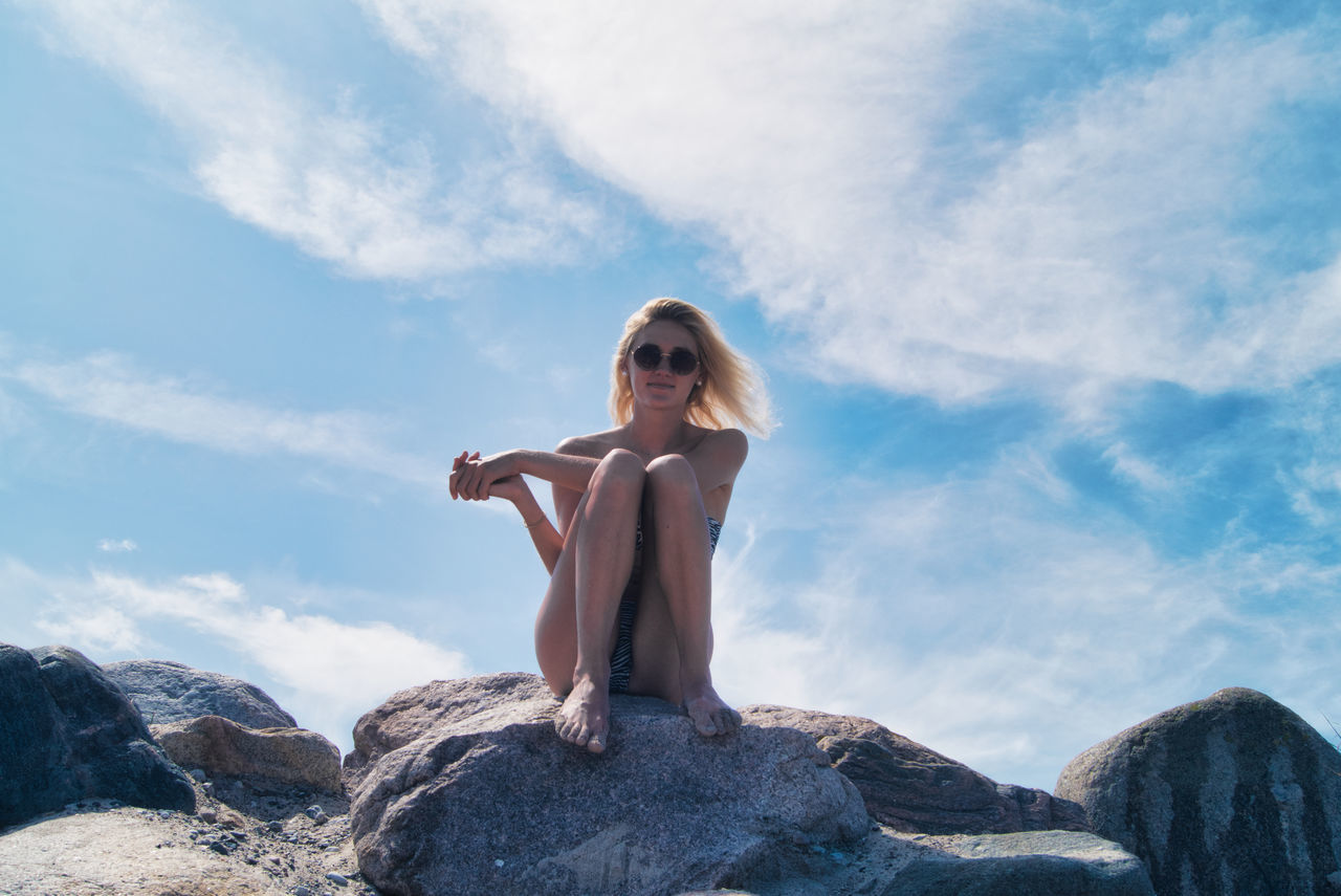 YOUNG WOMAN SITTING ON ROCK