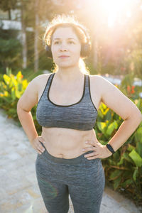 Portrait of young woman standing against trees