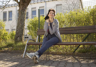 Pretty woman resting on bench holding poles after nordic walking. beautiful happy caucasian woman