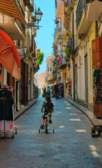 People riding motorcycle on street amidst buildings in city