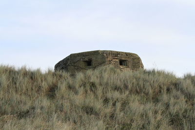 Low angle view of abandoned pill box on grassy field