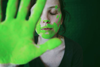 Close-up of woman gesturing with green hand