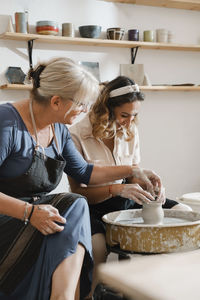 Teacher and student at pottery workshop learning to make bowls from clay. happy woman doing handmade