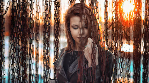 Portrait of young woman and chains at sunset