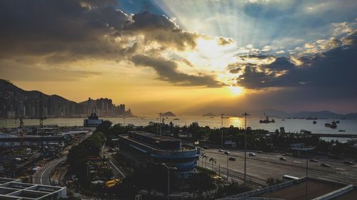 Panoramic view of coastal city against cloudy sky during sunset
